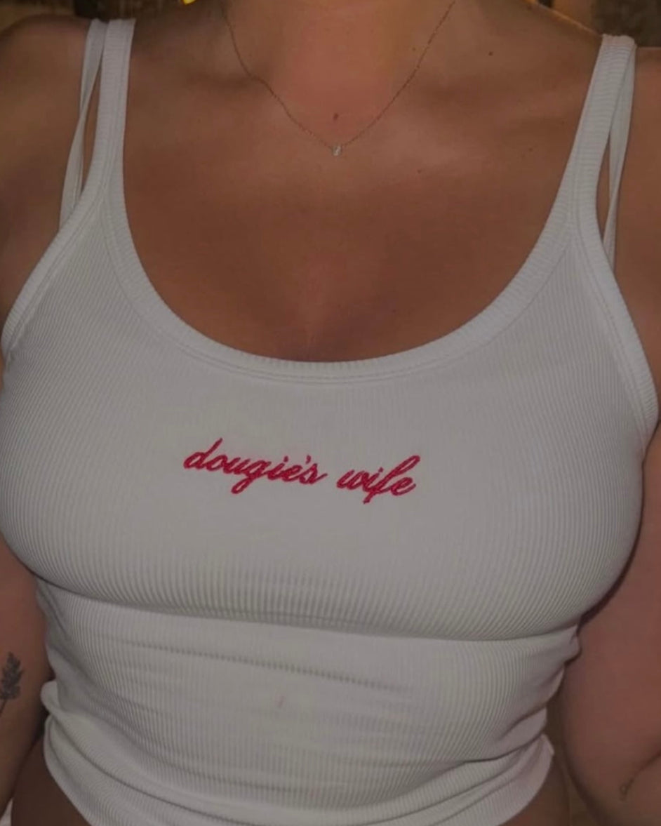 Person wearing a white tank top with 'dougie's wife' text in red.